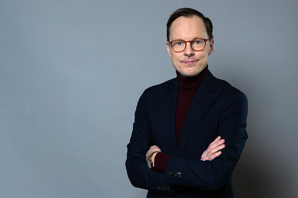 Man med armarna i kors och glasögon.